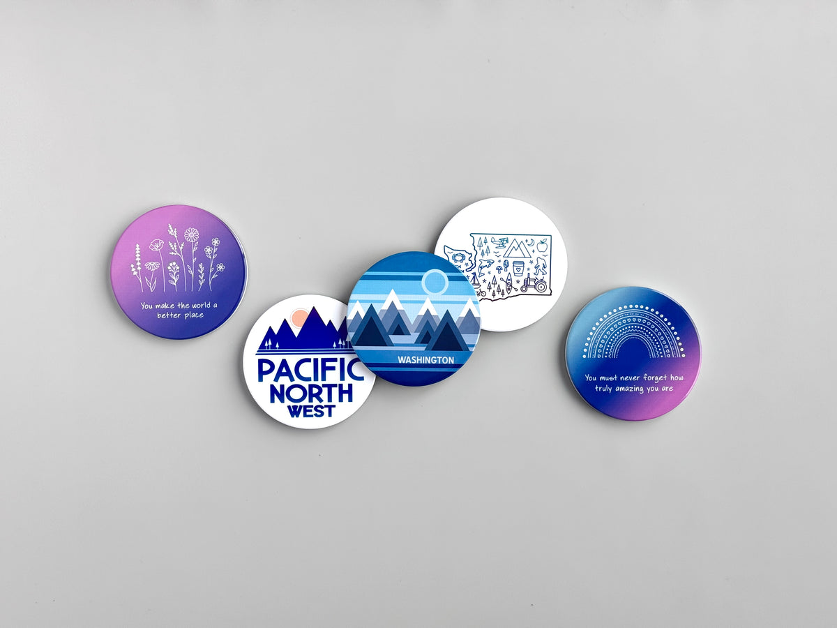 Five ceramic coasters with Pacific Northwest-themed graphics and quotes, arranged on a light gray background.