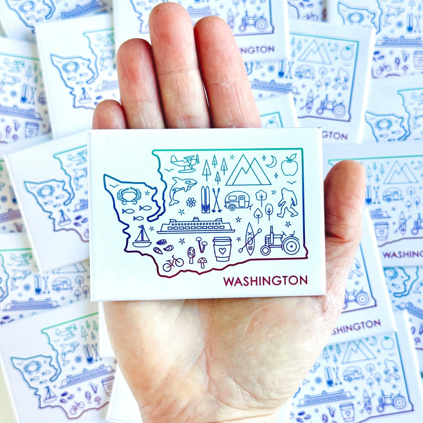 Hand holding a card with 'Washington' illustration surrounded by more cards with similar designs.