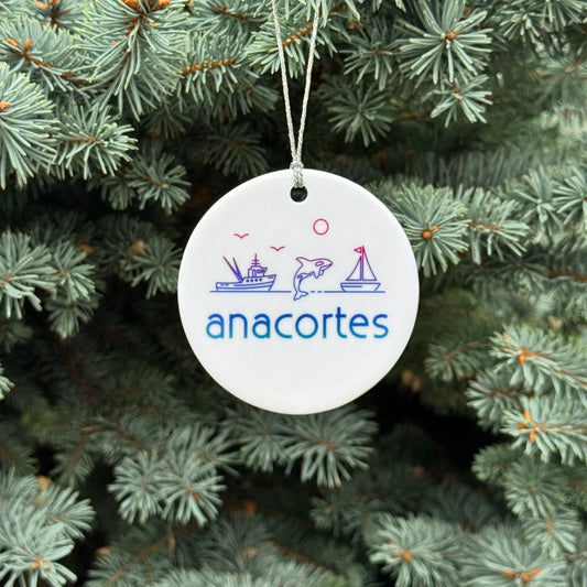 Decorative ornament with 'anacortes' text and graphics hanging on a Christmas tree.