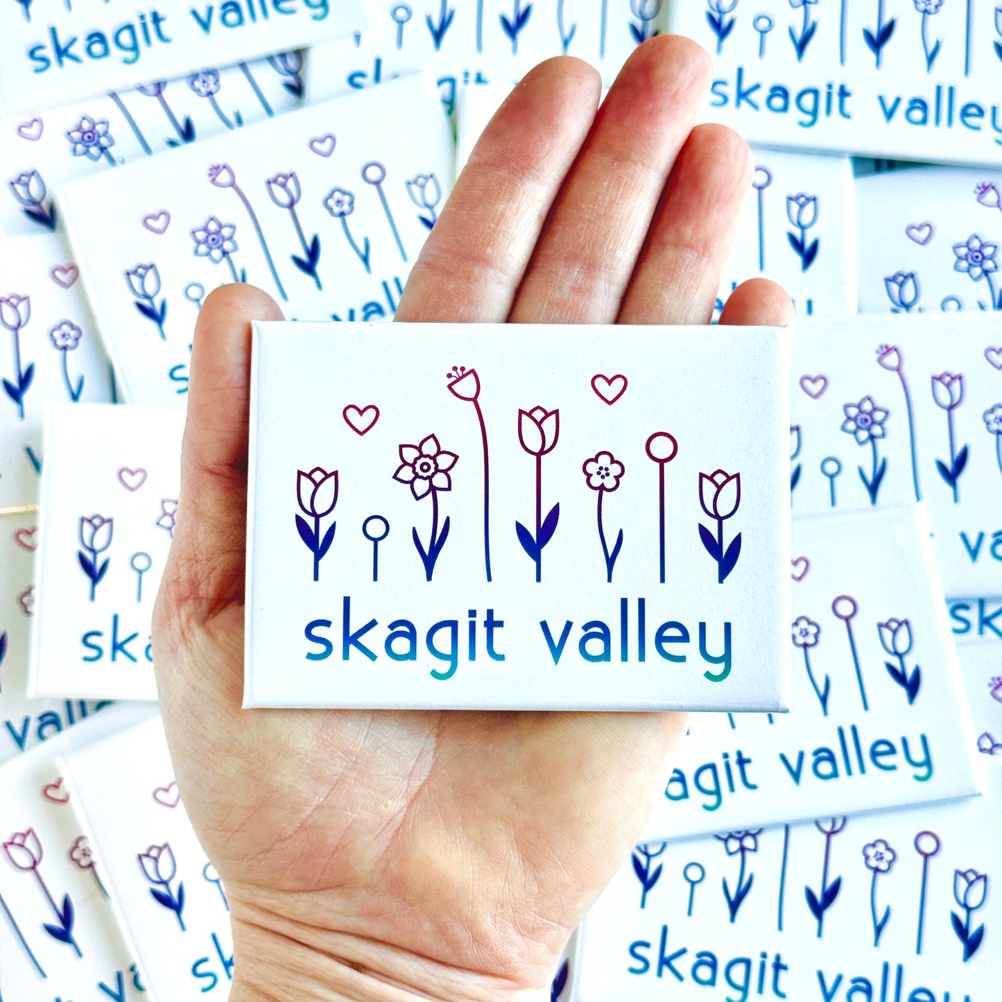 Hand holding a card with 'skagit valley' design surrounded by more cards with the same design.