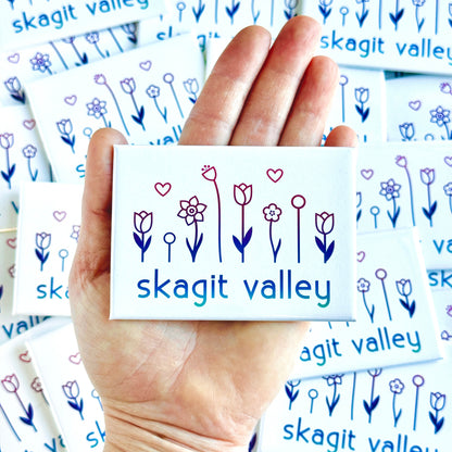 Hand holding a card with 'skagit valley' design surrounded by more cards with the same design.